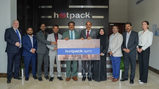Group of professionals hold a Hotpack Sustainability Report while posing in a corporate lobby